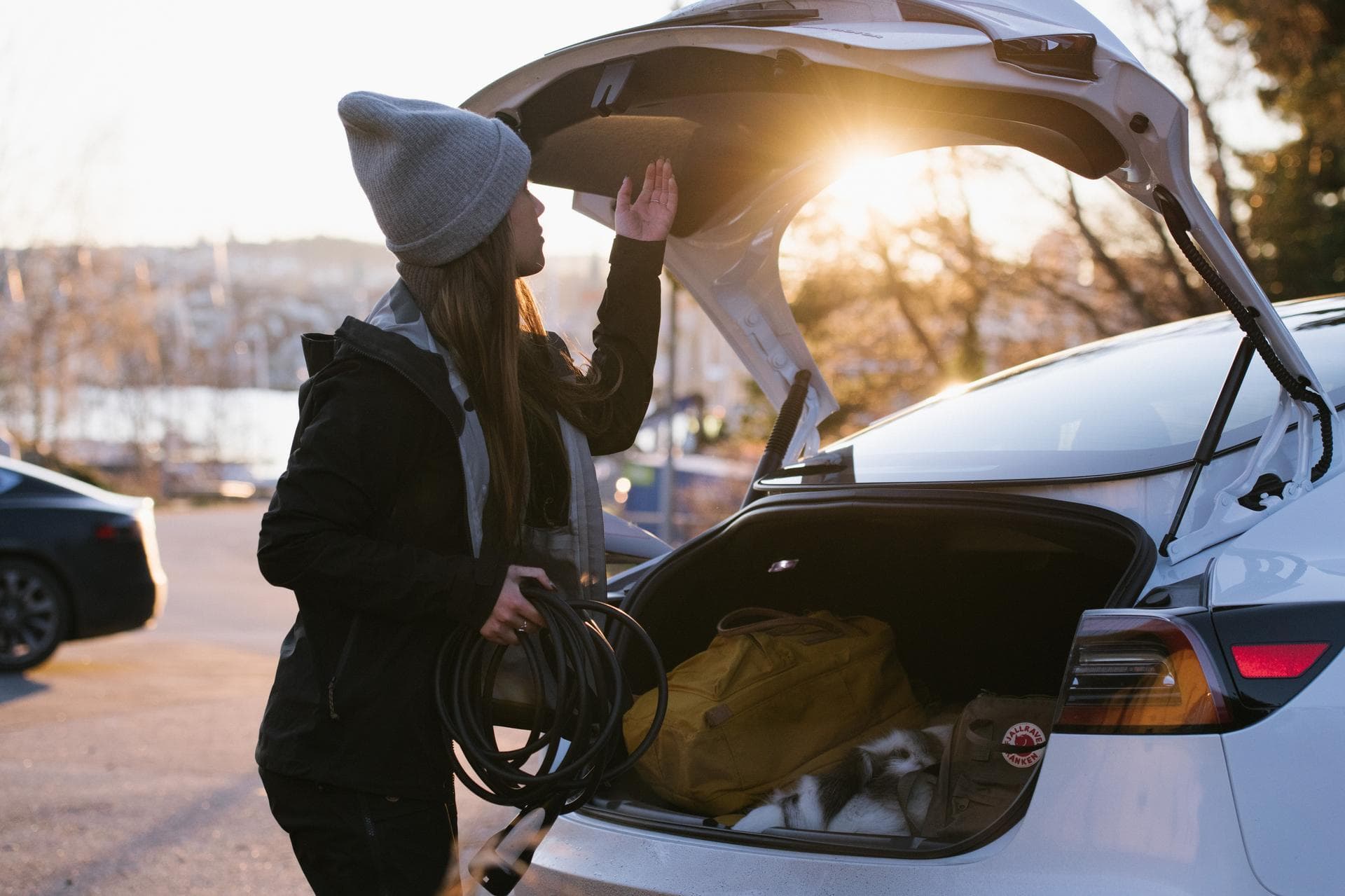 Eine Frau holt ihr Ladekabel aus dem Kofferraum, um Ihre E-Auto-Batterie aufzuladen