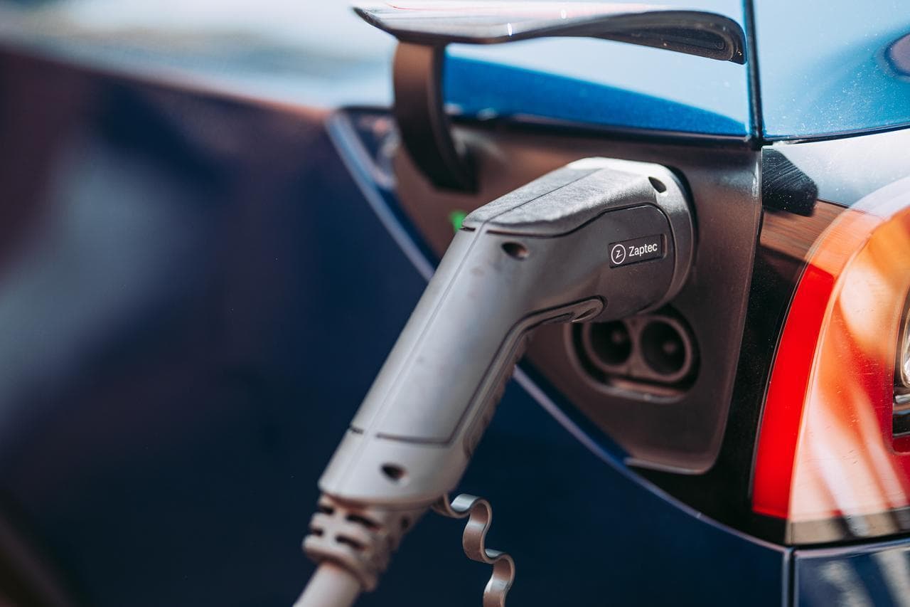 En laddkabel som sitter i ett ladduttaget på en blå tesla.