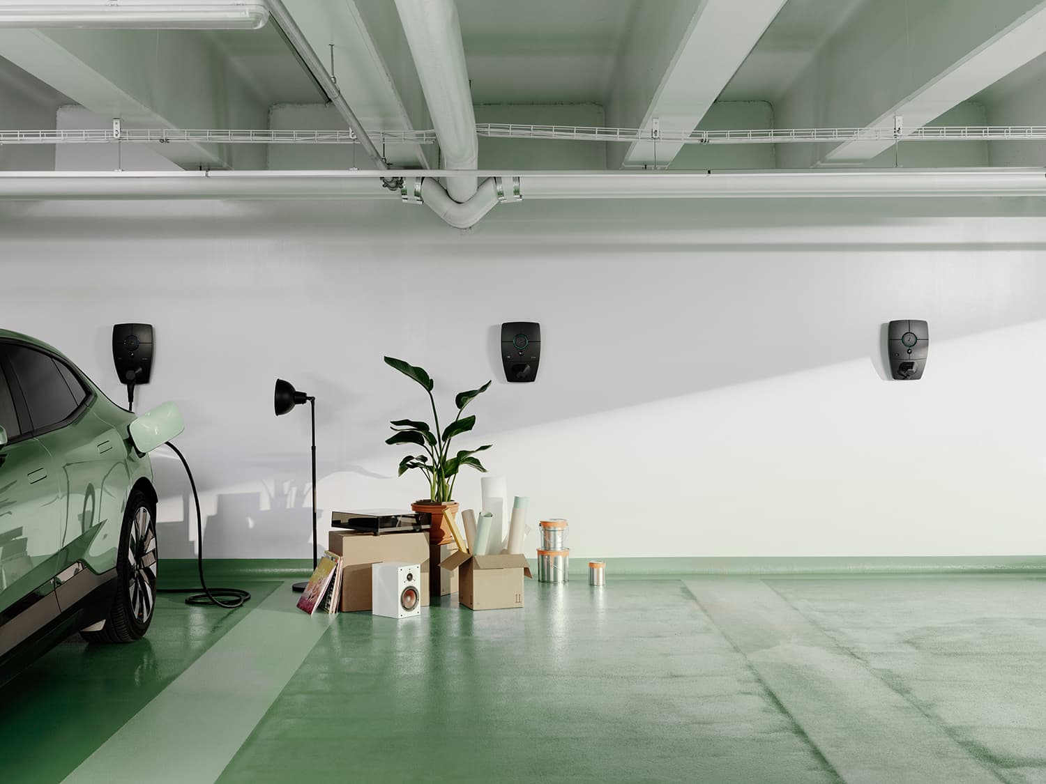 Grøn bil lader med Zaptec Pro lader på hvid væg i parkeringskælder, flyttesituation med kasser, lampe, plante og højttaler på grønt gulv.