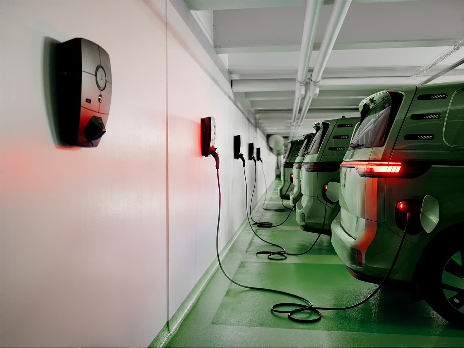 Rij groene bestelwagens laadt op met Zaptec Pro laders op witte muur in parkeergarage, rode achterlichten branden.