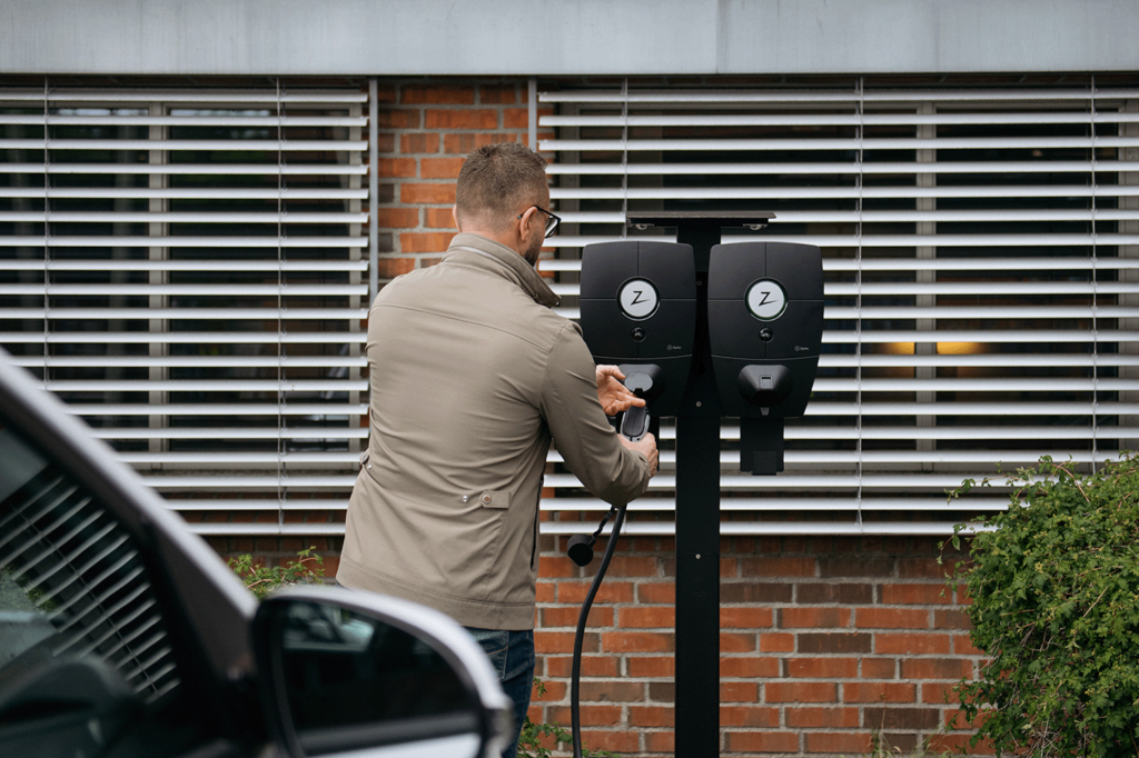 a man charges his electric car at a charging station